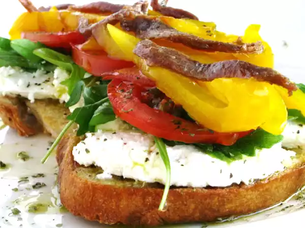 Receita Bruschetta de requeijão, rúcula, tomate, pimento e anchovas