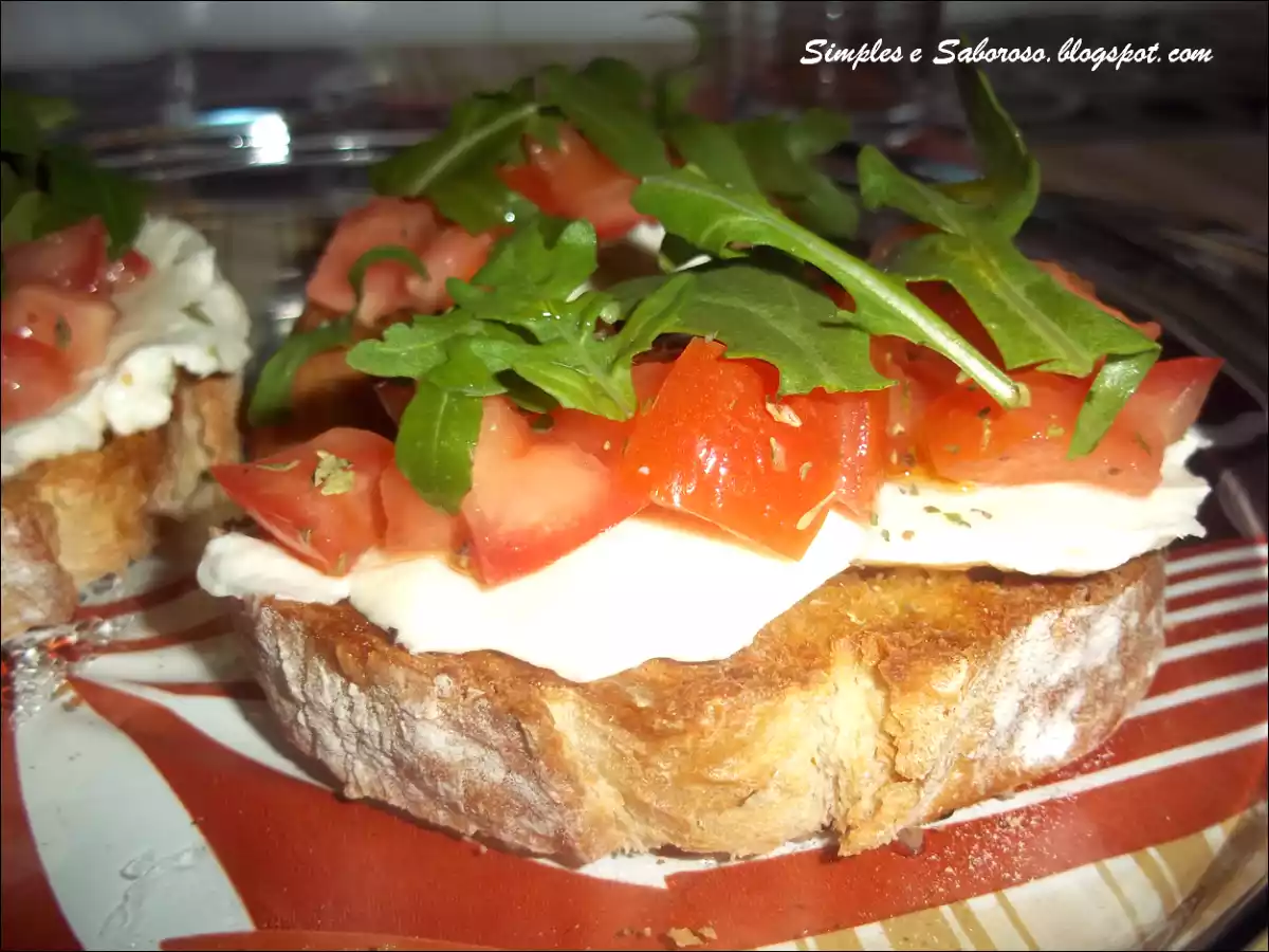 Bruschetta de queijo, tomate e rúcula