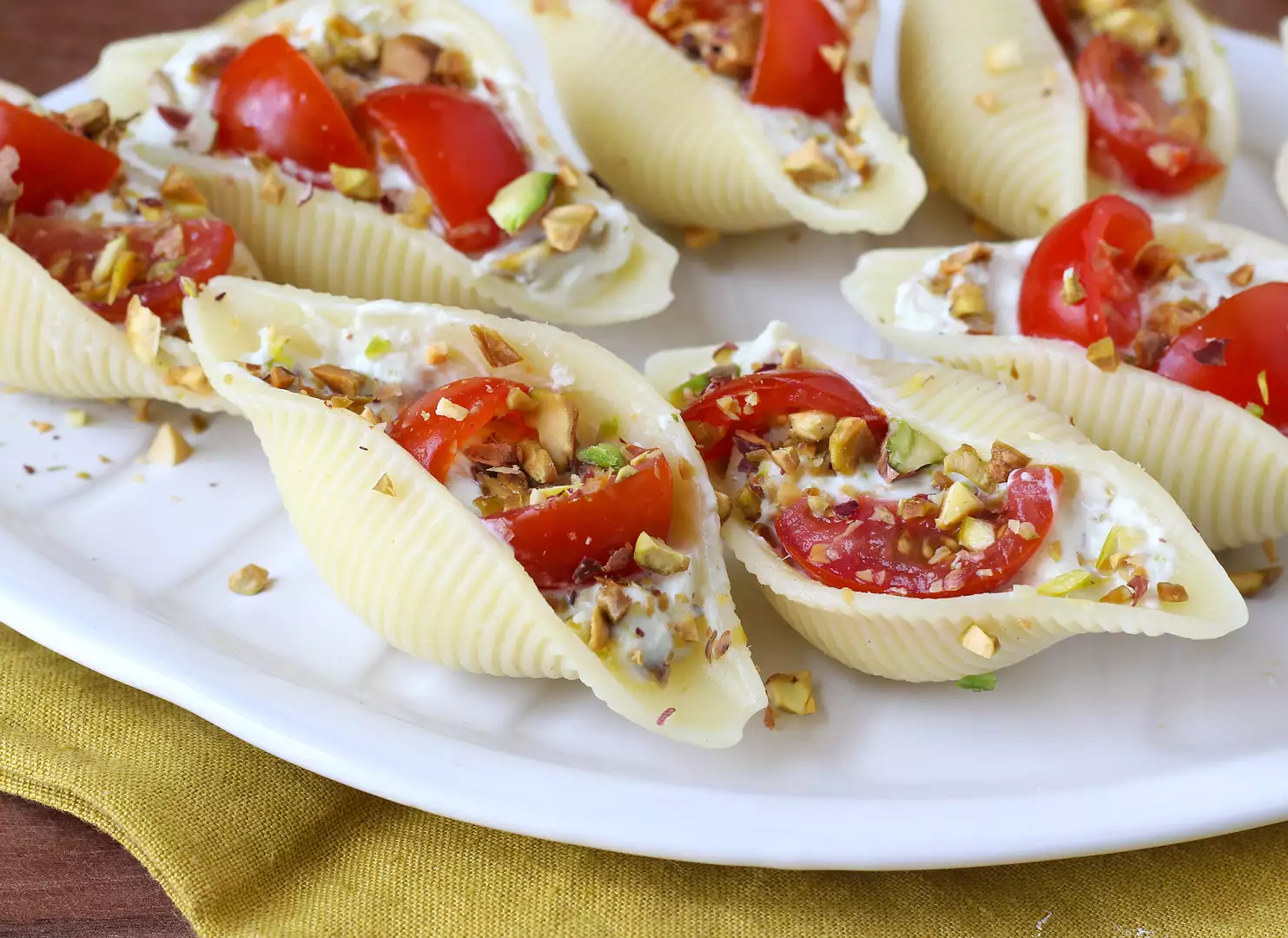 Conchiglioni recheados frios com stracciatella, pistache, tomates-cereja e limão